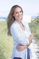 Langhaarige Frau in frühlingshaftem blau-weißem Outfit am Strand