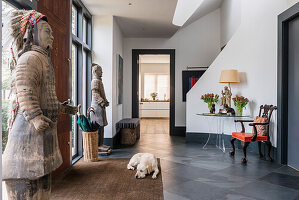 Hallway with statues, dog on carpet, table, chair and view of kitchen
