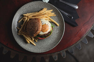 Breakfast burger with fried egg, cheddar cheese, ground bacon, beef patty, chips