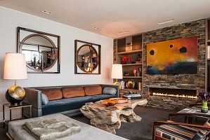 Solid wood coffee table, seating, antique lamps and mirror in living room with slate-clad wall