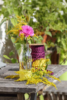 Dahlia and goldenrod in glass bottle