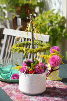 Autumn bouquet of dahlias, goldenrod and red snowball berries, above branch with wreath