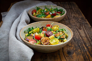 Two bowls of pasta salad with grilled zucchini, tomatoes, arugula, Spanish onion and balsamic vinegar
