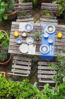 Gartentisch gedeckt mit bunten Tellern und Schalen