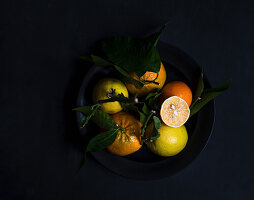Citrus fruits in a black bowl on a black background