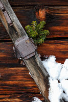 Ladder decorated with conifer branches in front of a wooden wall