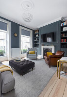 Upholstered furniture and leather armchairs in living room with grey walls