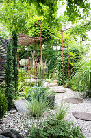 Gravel path with flagstones and climber-covered pergola in garden