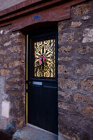 Christmas decorations on metal worked black front door of family home, France