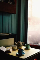 Tischplatte mit Teetassen, Untertassen und einer Teekanne in Café-Atmosphäre