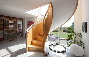 Sonnenbeschienene Wendeltreppe in der geräumigen Eingangshalle eines Hauses in Essex, UK