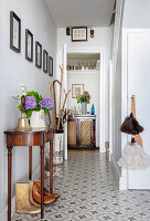 Antique console on narrow hallway with patterned tiled floor