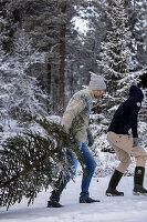 People with Christmas tree in a wintery forest