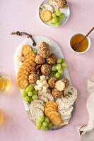 Cheese balls on a cheese board with crackers and grapes