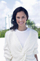 Dark-haired woman in white top and white wrap-around cardigan