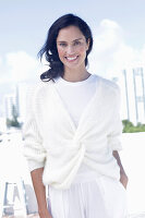 Dark-haired woman in white top and white wrap-around cardigan
