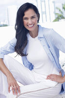 Dark-haired woman in a white top, light blue shirt and white trousers