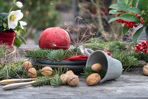 Weihnachtsdekoration mit Koniferenzweigen, Samenstand von Fenchel, Granatapfel und Walnüssen