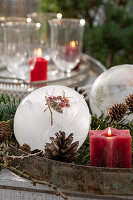 Ice ball with rose hips, cones and red candle