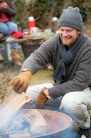 Man puts log in the fire bowl