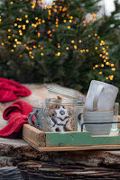 Glas mit Zimtsternen und Keramikbecher auf Holztablett