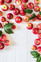 Rote Äpfel mit Blättern auf weißem Holzuntergrund