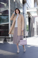 Brunette woman in turtleneck, skirt and beige leather coat