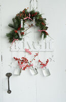 Garland of fir branches and hanging vases with holly berries