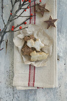 Assorted cookies in parchment on a dish towel with holly and wooden stars