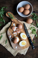 Hard boiled eggs, partly peeled, on a wooden board