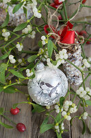 Christmas tree ball with bird motif between mistletoe and cones with birdseed