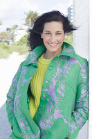 Mature, dark-haired woman in a green coat and green and yellow knit sweater
