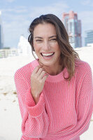 A laughing, long-haired woman wearing a pink jumper