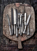 Vintage cutlery on a rustic wooden cutting board