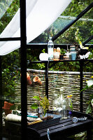 Black painted potting table with bottles in the greenhouse