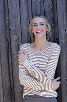 Young blond woman in striped shirt in front of board wall