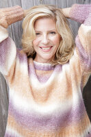 Mature blonde woman in knitted jumper with colour gradient