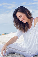 Long haired woman in white jumper and white trousers at the beach