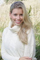 Junge blonde Frau in weißem Rollkragenpullover in der Natur