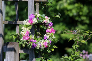 Kranz aus Holunderblüten, Wiesenkerbel und Wicken am Zaun