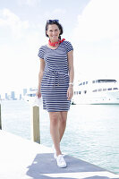 Brunette woman in a striped summer dress by the sea