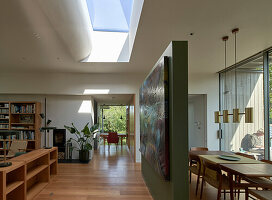 Open living room with green painted room divider and skylight