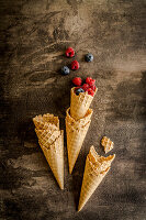 Several ice cream cones, one with fresh berries