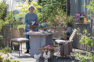 Woman sets table with Easter decorations on the terrace