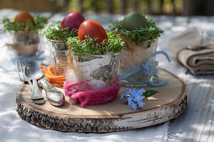 Easter eggs with cress in glasses on wooden tray and cutlery, Easter decoration