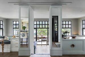 Kitchen-living room in split-level house, columns with recessed glass cabinets and mirrors