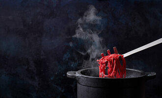 Lifting cooked beetroot noodles out of the pot