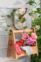 Frische Erdbeeren und Rosen in Flaschenträger als sommerliche Dekoration