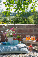 Bouquet and jug with strawberries on cushion in garden next to bench with drinks