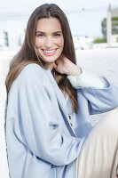 Young woman in light blue coat and light coloured trousers